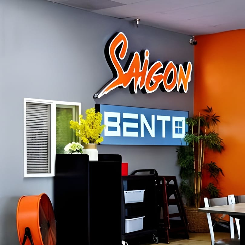 Saigon Bento restaurant interior with orange and blue signs, a window, and an orange wall.